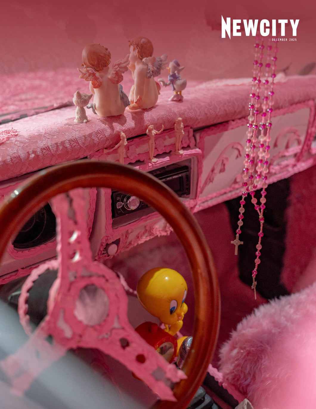A car decked in pink plush, with angel and animal figurines, a beaded rosary, a Tweety Bird toy by the wooden wheel—channeling The Little Review’s play. 