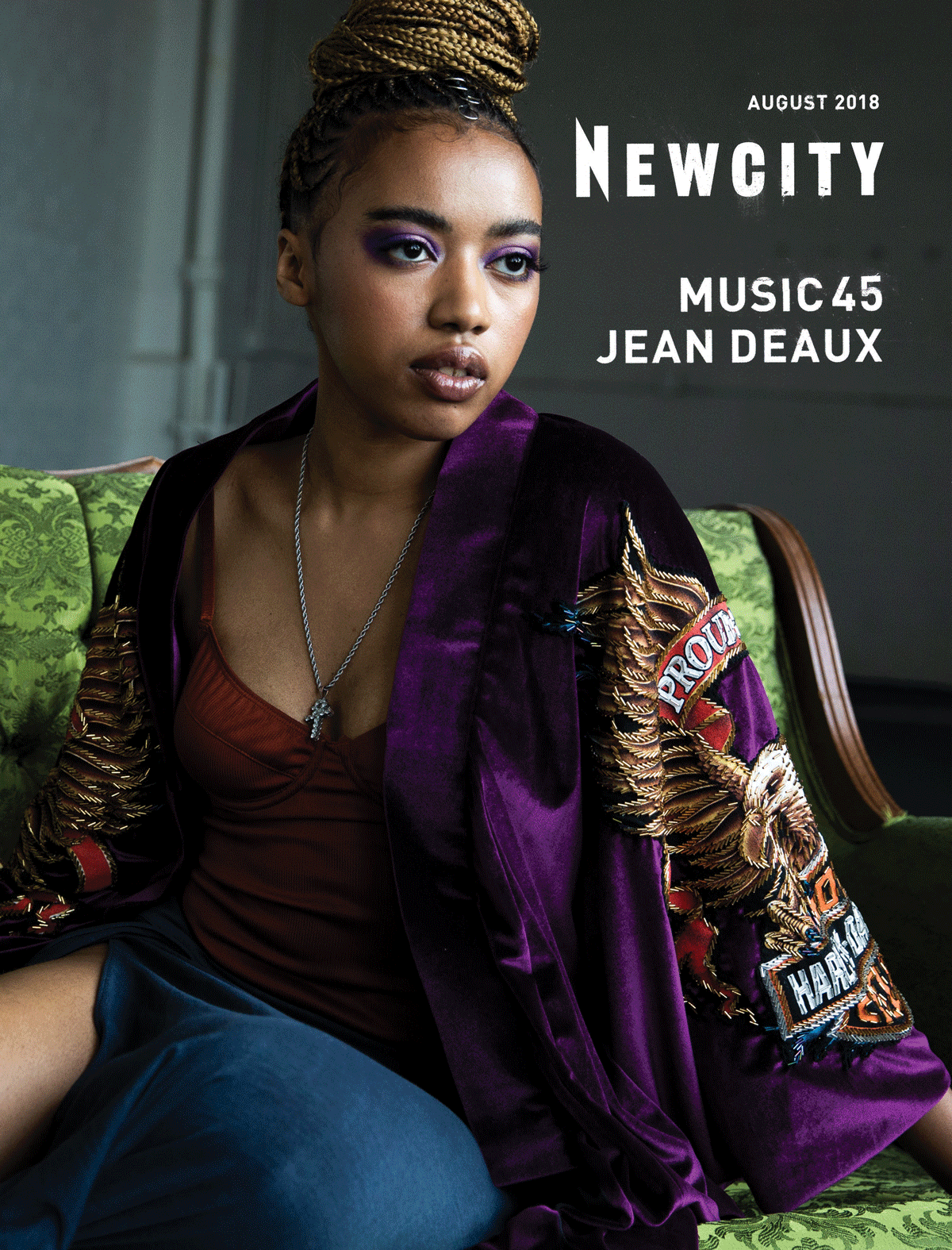 A woman with braided hair sits on a green vintage sofa, wearing a purple embroidered jacket and a red top. The cover text reads “NEWCITY August 2018, Music 45, Jean Deaux.” The August 2018 Issue: Music 45 spotlights the vibrant Chicago music scene and celebrates rising artist Jean Deaux, whose sound brings feminist energy to the festival spirit of Lollapalooza.